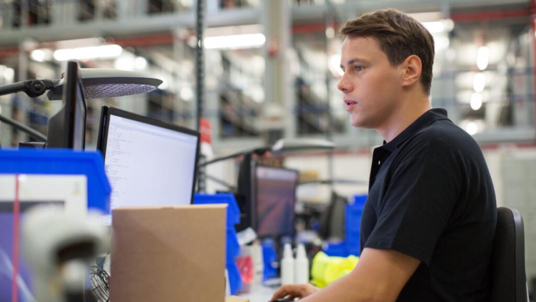 Warehouse worker on a computer at a desk within the warehouse