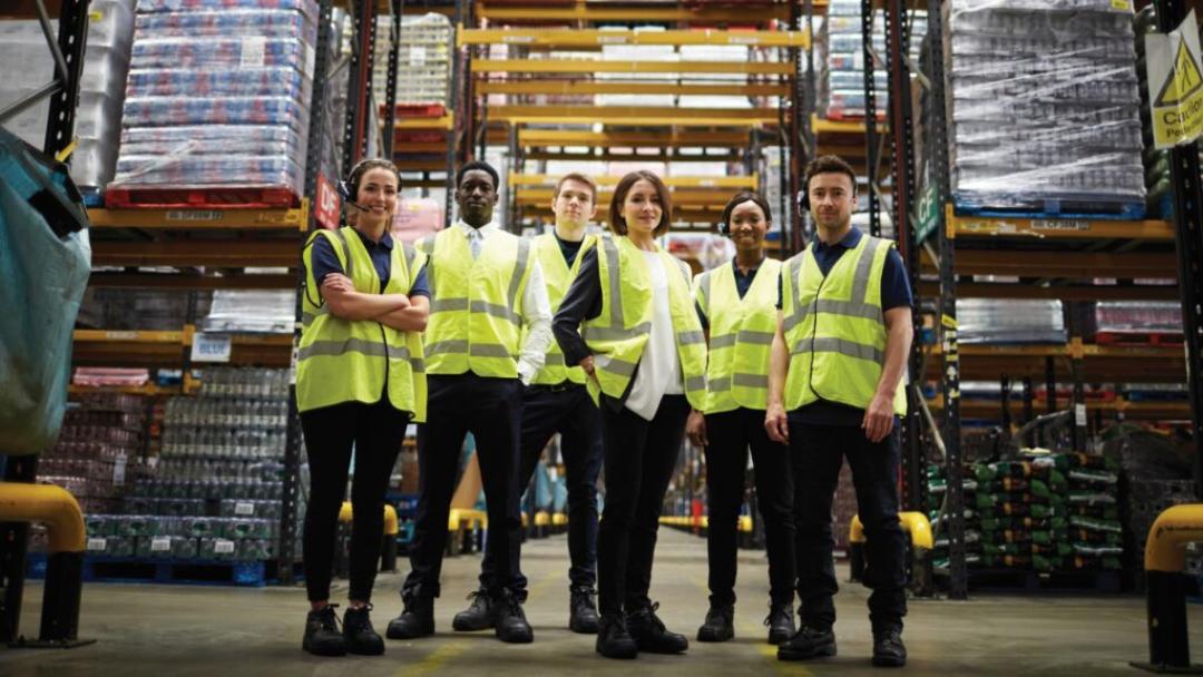 Warehouse team in yellow reflective vests posing in line