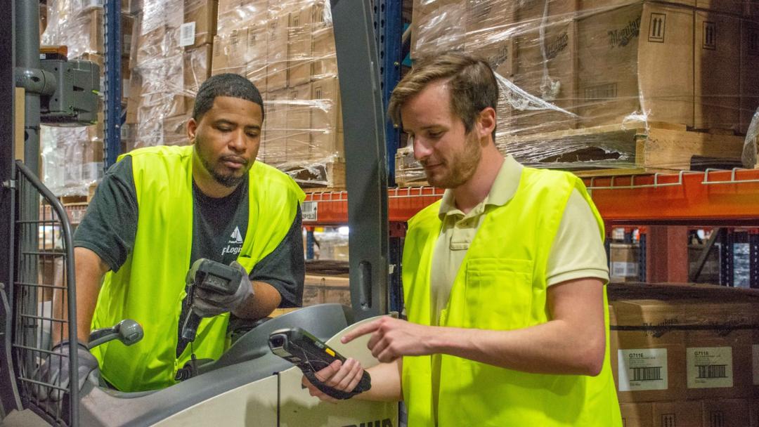 Two warehouse workers in yellow talking