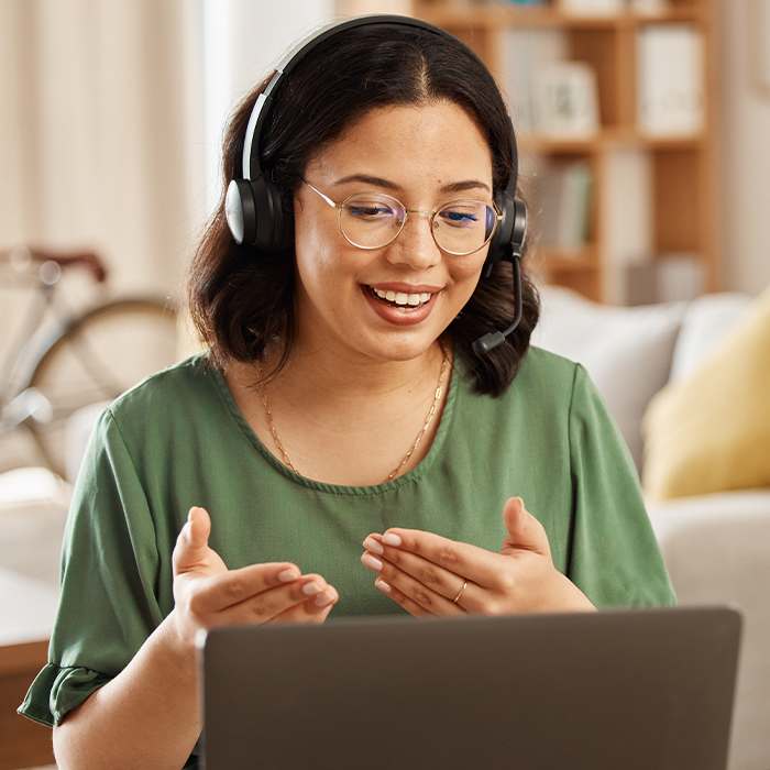 girl wearing green shirt talking on a video call to a laptop 