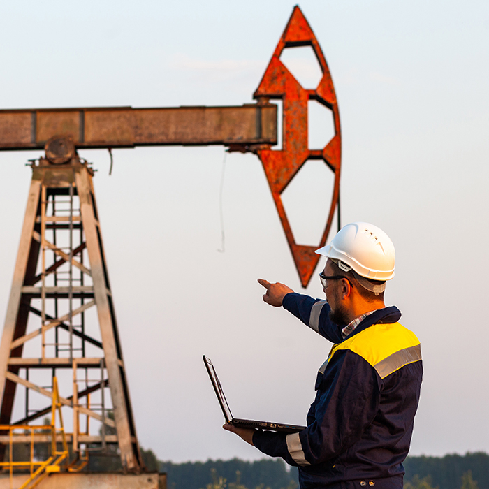 a man wearing a white construction hat point towards an oil rig