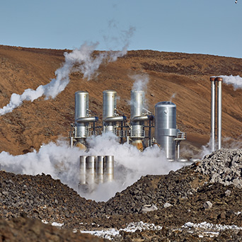 smoking pipes in a power plant surrounded by gravel and mountains