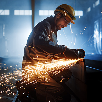 Manufacturing worker using machinery with large sparks