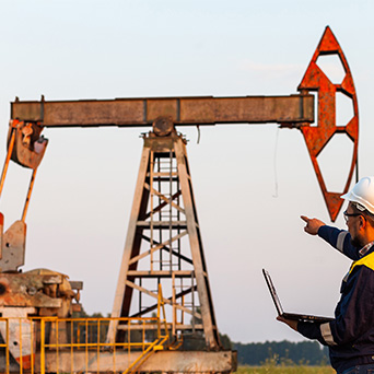 a man wearing a white construction hat point towards an oil rig