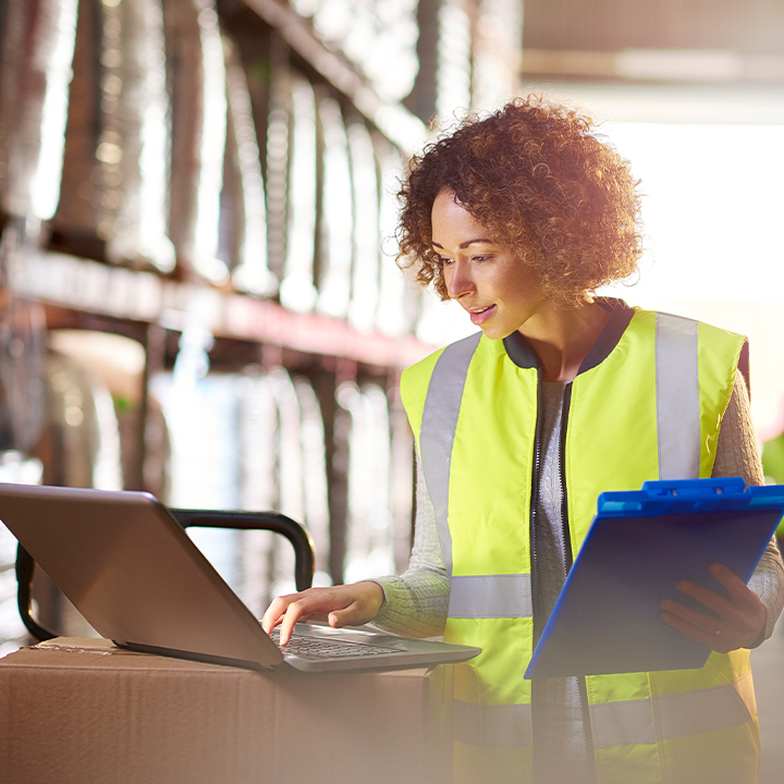 Worker looking on computer wearing safety vest