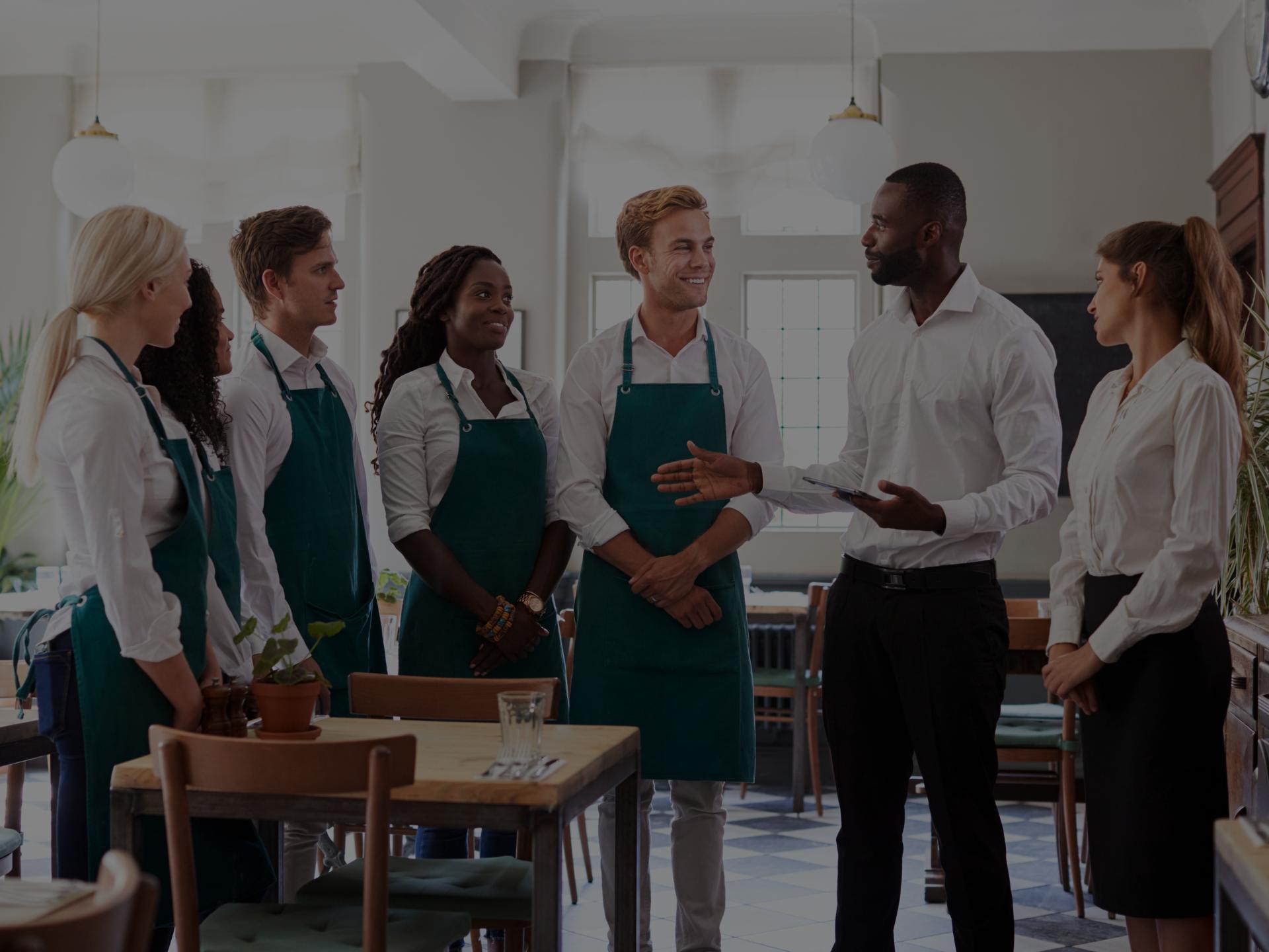 Restaurant staff and managers speaking in dining room.