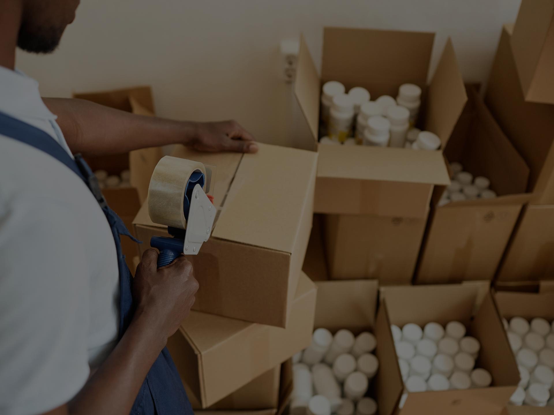 Worker filling boxes with white pill bottles. 